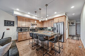 A modern kitchen with wooden cabinets, stainless steel appliances, and a central island with bar stools.