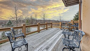 A wooden deck with metal chairs and tables, overlooking a cityscape. - Cozy Luxury Almost Ski-in Ski-out with Hot Tub in Southwind! (Seven Springs)
