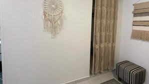A room with a macramé wall hanging, a macramé curtain, and a patterned bench.