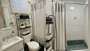 A bathroom with a toilet, sink, and shower. There is a shelf with towels and toiletries. The shower has a curtain.