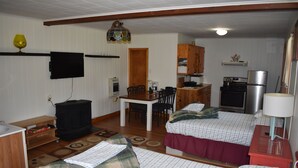 A compact room with two beds, a dining table, a kitchen area with a refrigerator and stove, and a television mounted on the wall. - Studio Suite with 2 beds - Located at the Heart of Promised Land State Park  (Greentown)