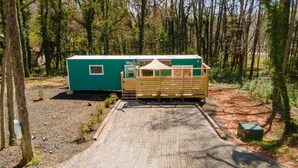 Eine kleine, eingeschossige Holzhütte mit grüner Fassade und einer Holzterrasse.