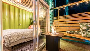 Ein gemütliches Schlafzimmer mit einem Bett, einem kleinen Tisch mit Feuerstelle und einer Bank mit Kissen.