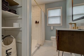 Un baño con ducha, inodoro y tocador con espejo.