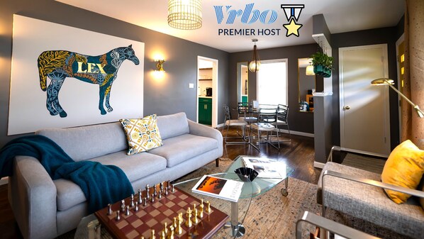 Una sala de estar moderna con un sofá gris, una mesa de ajedrez y un mural en la pared con un caballo.