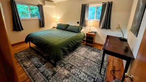 A bedroom with a bed, two bedside tables, a desk, a rug, and windows with curtains. - Sweet 3 Bedroom, Walk to Main St! (Independence)