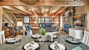 A cozy cabin interior with a dining area, living room, and a fireplace.