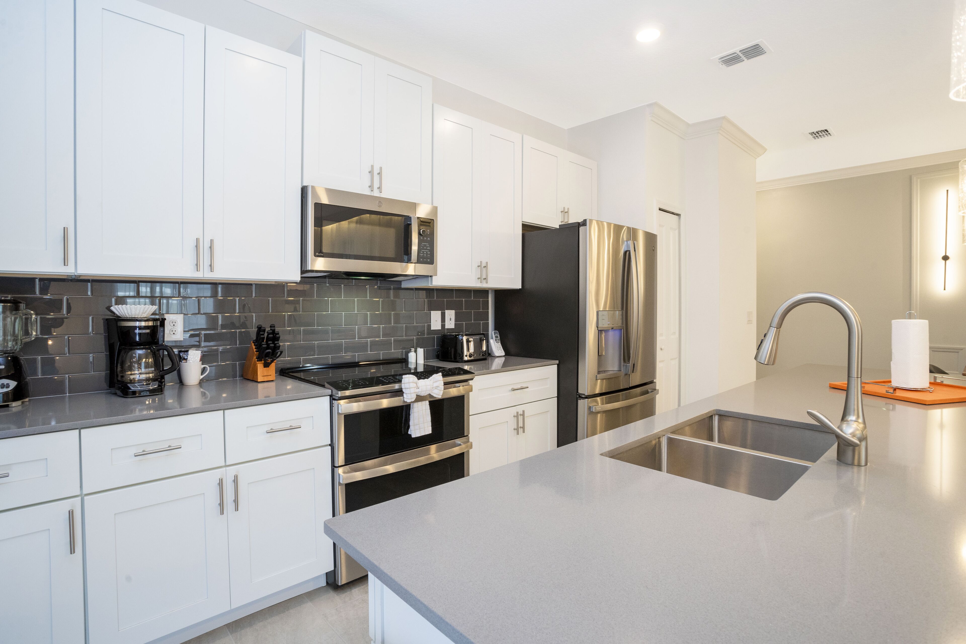 A modern kitchen with white cabinets, stainless steel appliances, and a grey countertop.