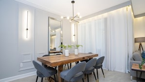 A modern dining area with a wooden table, grey upholstered chairs, and a large mirror above.