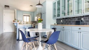 Una cocina moderna con armarios azul claro, una mesa redonda blanca y sillas azules, además de una lámpara colgante.