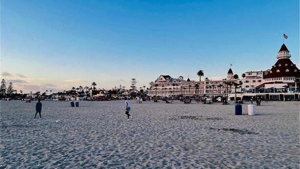 Una playa con un hotel grande al fondo.