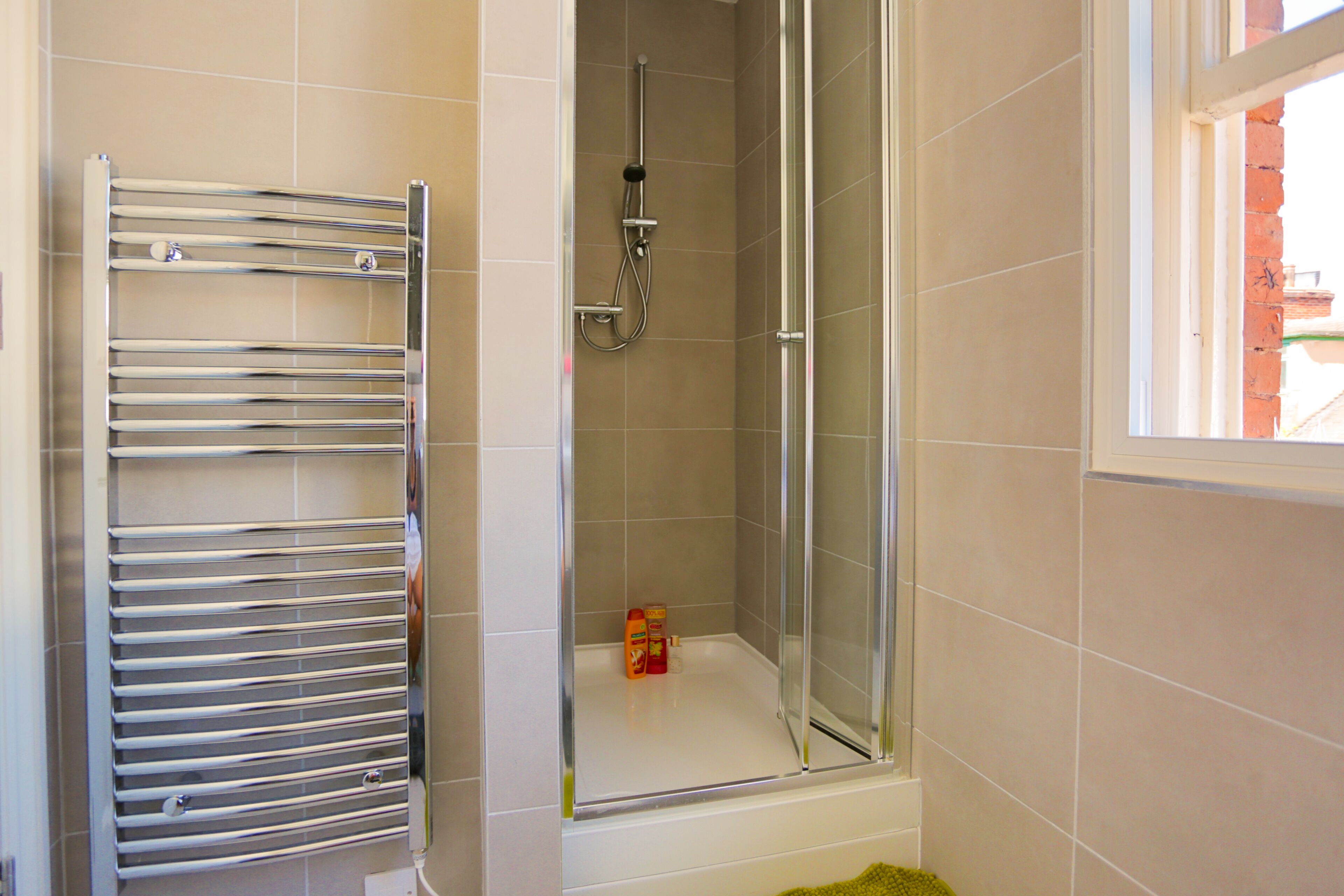 Une salle de bain avec une douche à parois de verre, un porte-serviettes chromé et un petit flacon de shampoing.