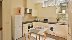 Cocina compacta con refrigerador, microondas, tostadora y lavadora.