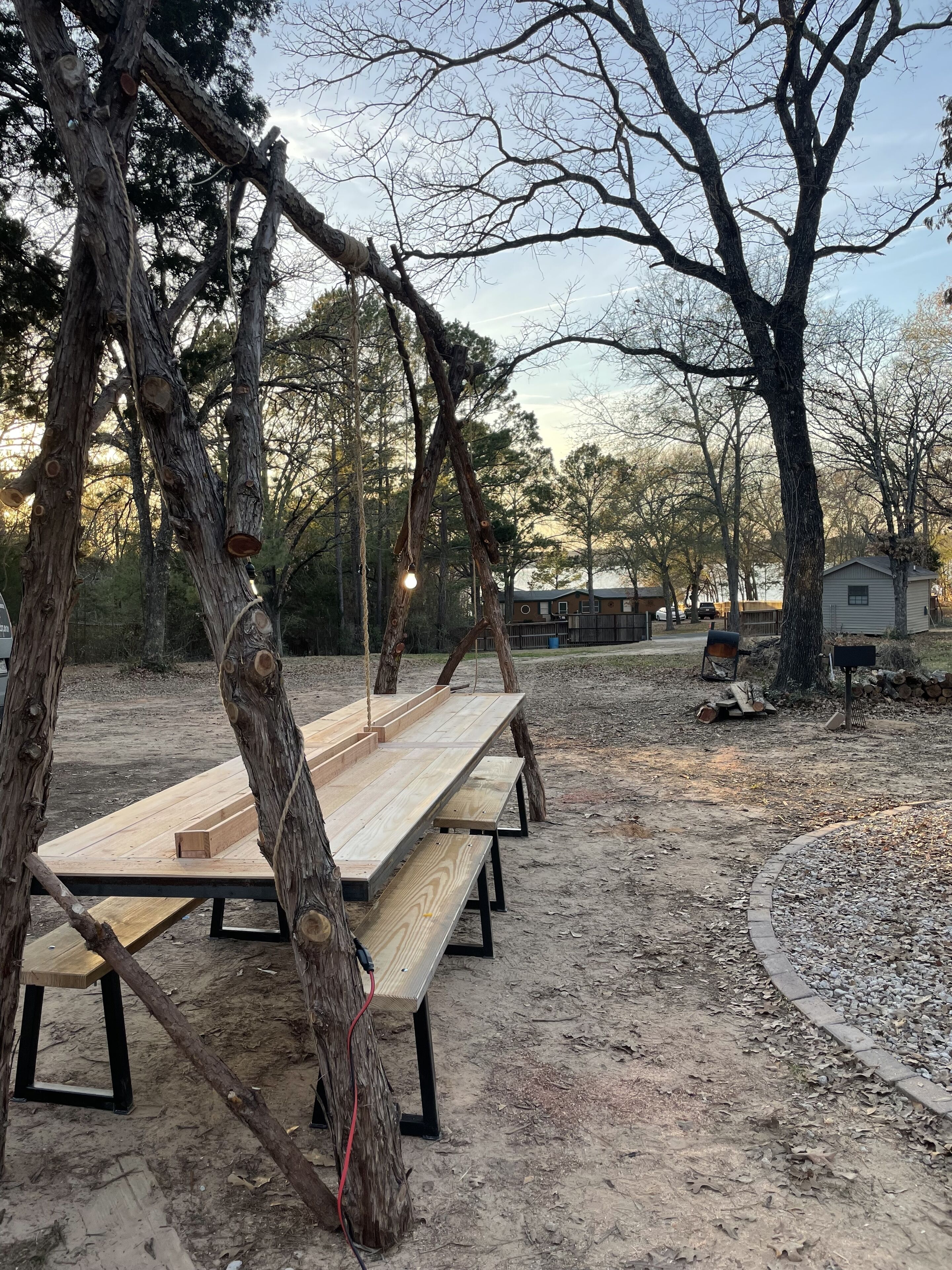 A picnic area with wooden benches and tables, surrounded by trees.