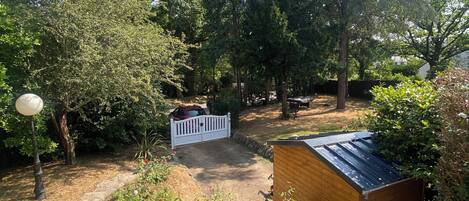 Ein Garten mit einem Kiesweg, einem Holzschuppen und einem weißen Zaun.