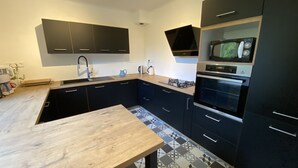 Una cocina moderna con armarios negros, encimera de madera, un lavabo, una estufa y un horno.