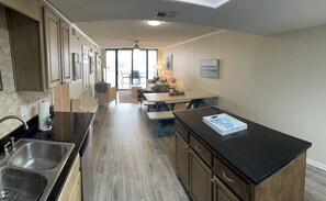 Enjoy meals in this kitchen with a stainless steel sink, wooden cabinets, and a dining area with a table and chairs.