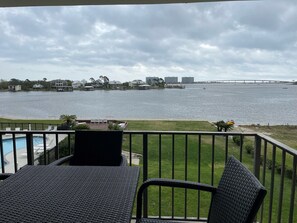 A balcony with wicker furniture overlooking a body of water, a bridge, and residential buildings. - Best Views in Orange Beach!! (Orange Beach)