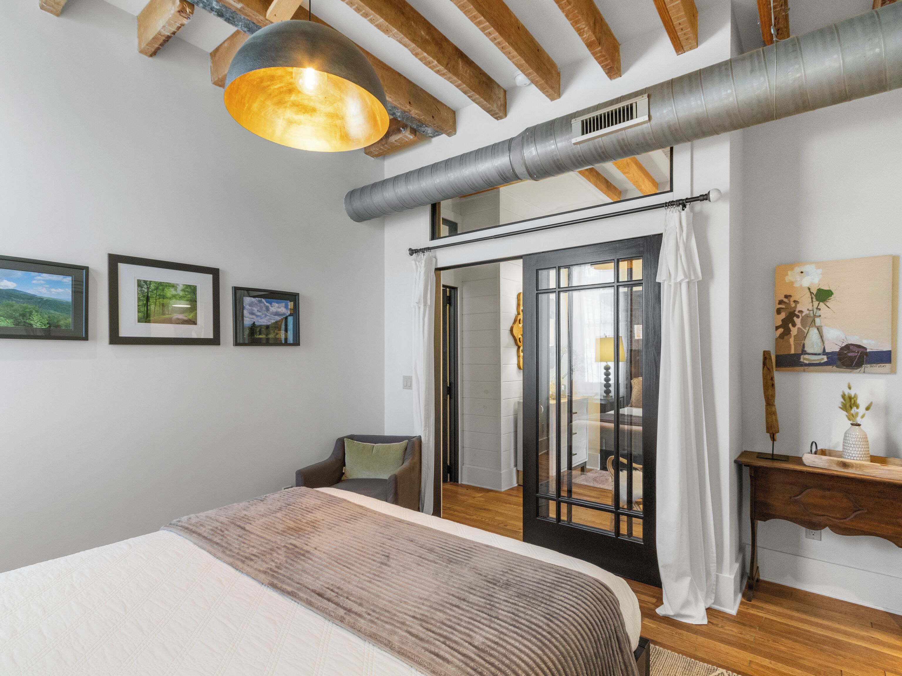 Une chambre à coucher avec un lit, un bureau, une chaise et une grande fenêtre.