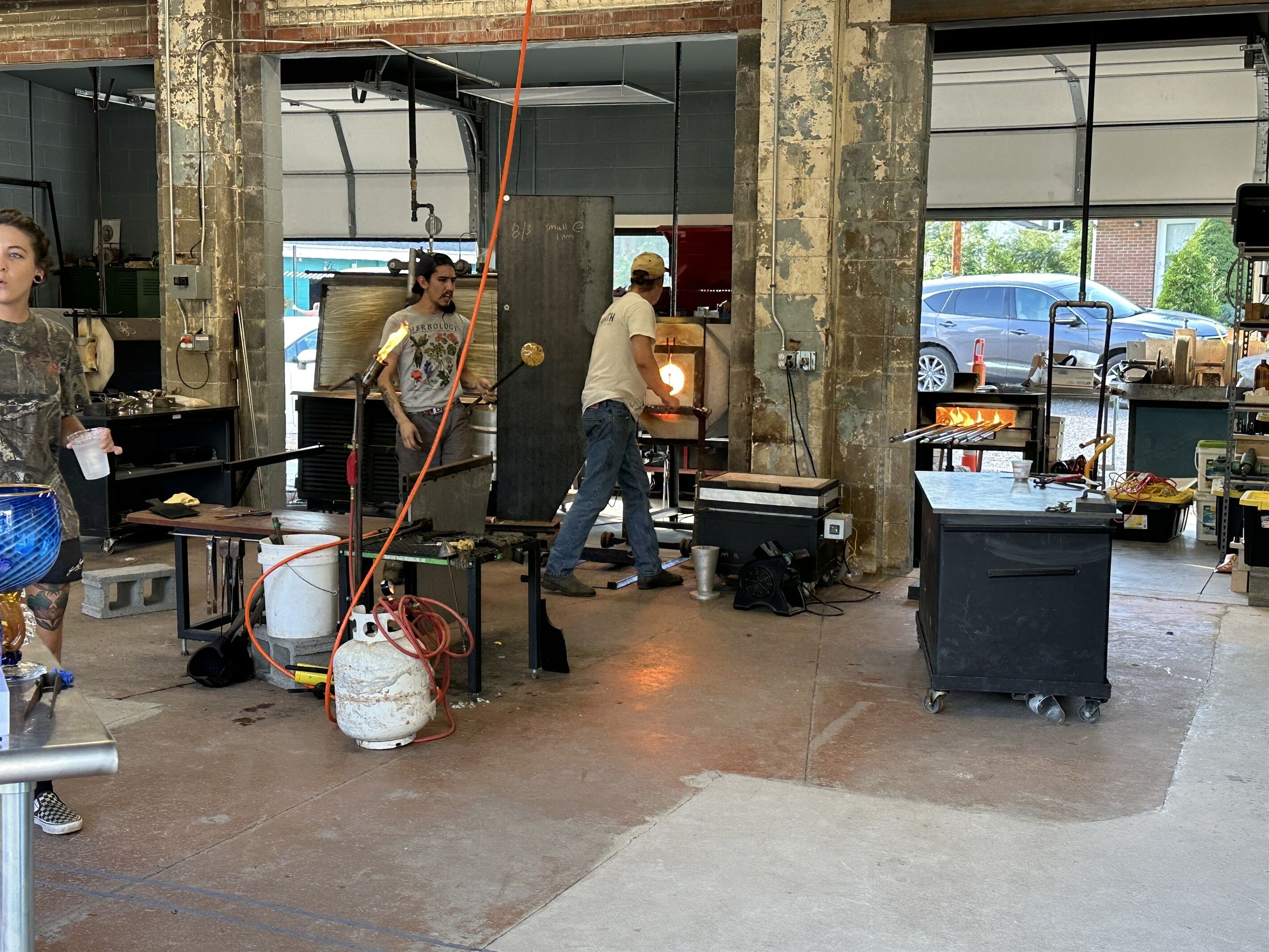 Un atelier où deux personnes travaillent sur une grande structure métallique, avec des outils et du matériel éparpillés autour d’elles.