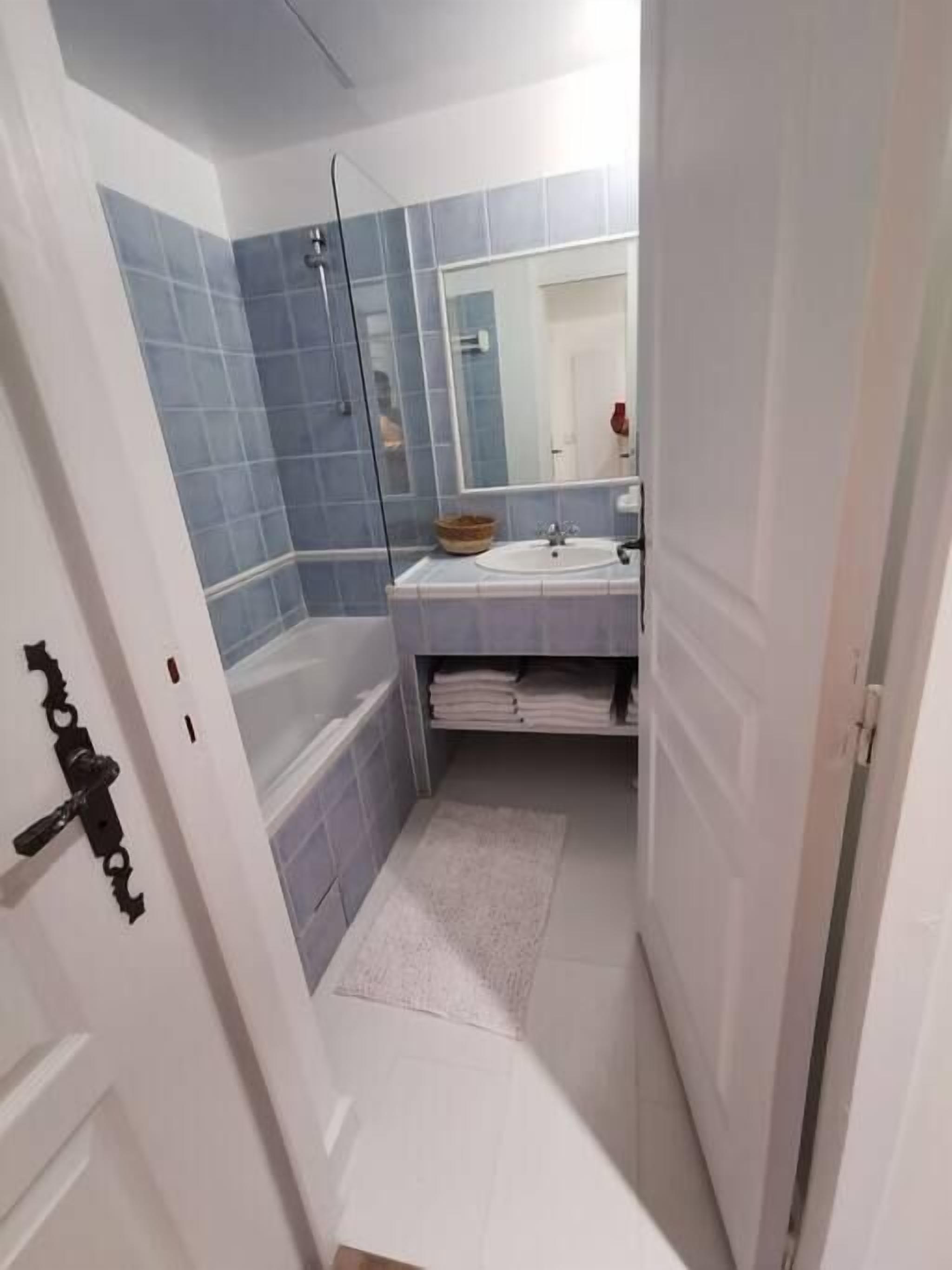 A bathroom with a bathtub, a sink, and a mirror.