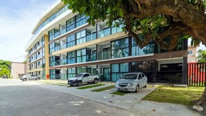 Un edificio moderno a più piani con ampie finestre e un'area di parcheggio con tre automobili.
