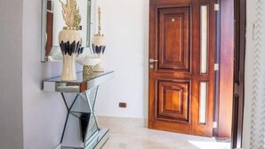 Um interior moderno com um sofá branco, um travesseiro fofo, um espelho e uma porta de madeira.