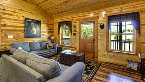 Interior acogedor de una cabaña con un sofá, una mesa de centro de madera y un tapiz temático de osos.