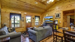 Un acogedor interior de cabaña de madera con un sofá, un televisor y una mesa de comedor.
