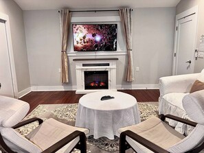 A living room with a fireplace, a television mounted above it, and two armchairs.