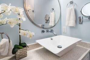 A bathroom with a white sink, a round mirror, and a towel rack.