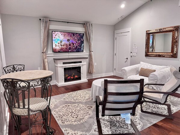A living room with a fireplace, a television, a sofa, and a dining table with chairs.