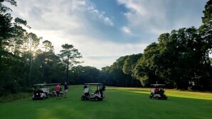 En golfbane med tre golfbiler og spillere.