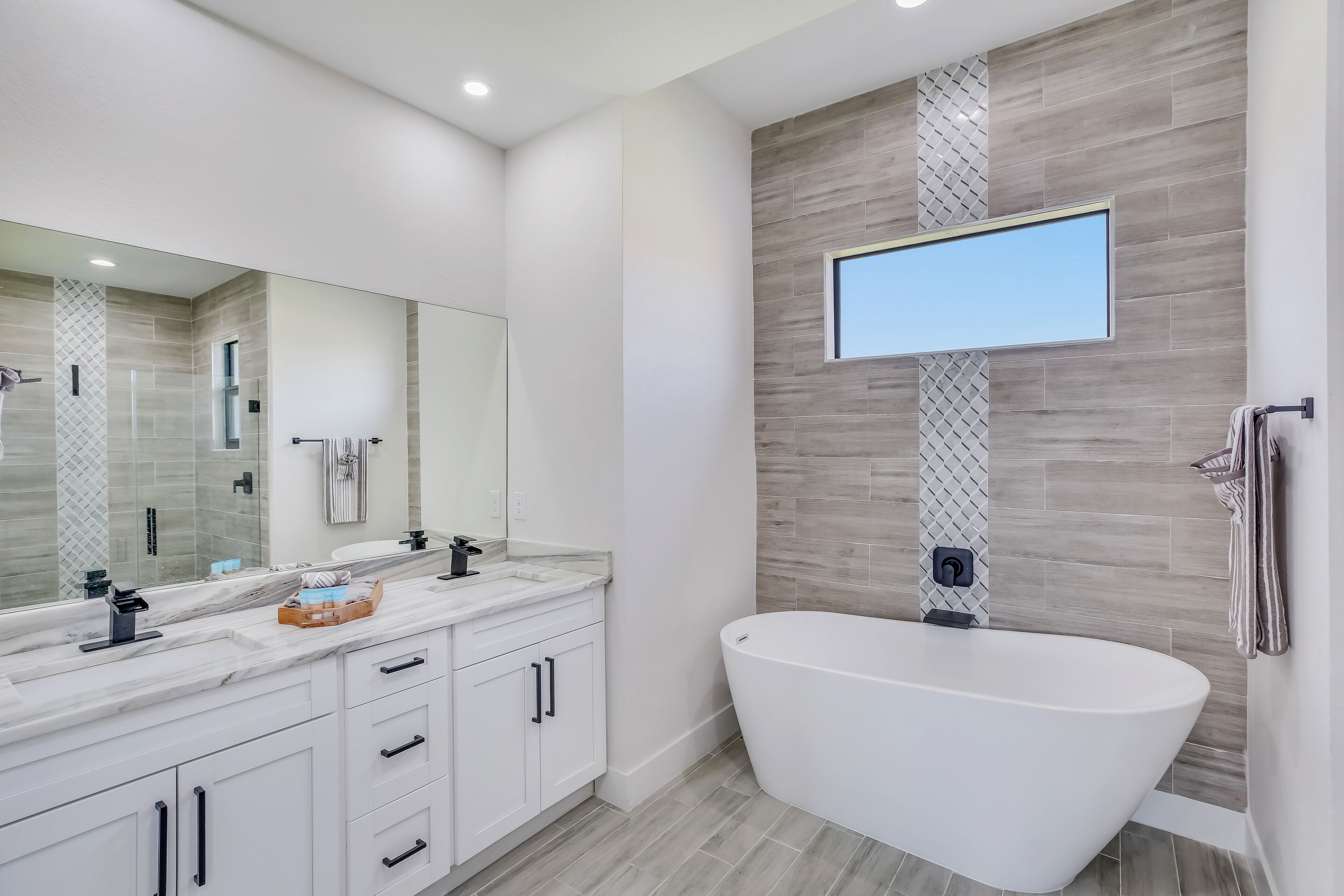 Une salle de bain moderne avec une baignoire sur pieds, un grand miroir et un meuble-lavabo doté d’un plan de travail en marbre.