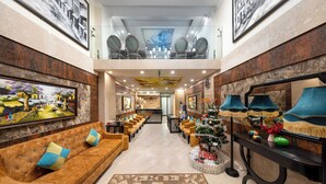 A spacious lobby with a high ceiling, a central staircase, and a Christmas tree. - Golden Legend Palace Hotel (Hanoi)