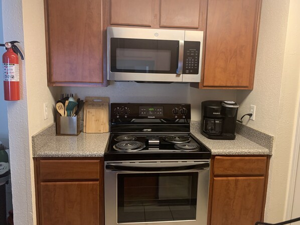 A kitchen with a stainless steel stove, a microwave, and a Keurig coffee maker.