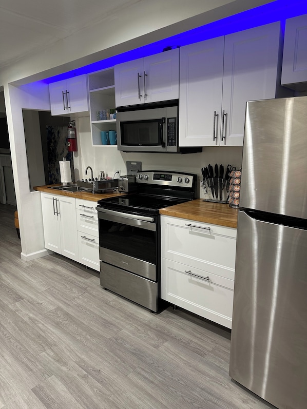 A modern kitchen with white cabinets, a stainless steel refrigerator, a microwave, an oven, and a sink. - Beach house apartment 2 blocks from the beach #3 (Panama City Beach)