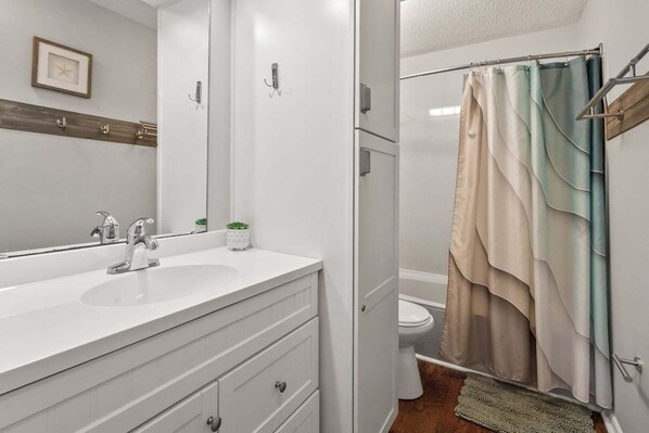 A bathroom with a double sink, a mirror, a towel rack, and a shower curtain. - Golf and family-friendly rental w/pool, hot tub-1 block from beach in Ocean Drive (North Myrtle Beach)