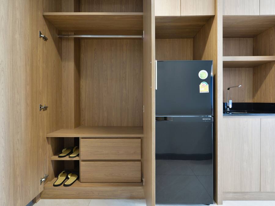 Una cocina moderna con muebles de madera, un refrigerador negro y estantes empotrados.