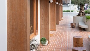 A corridor with wooden columns, potted plants, and a brick floor. - VST Punnawithi (Bangkok)