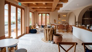 A spacious indoor area with wooden beams, large windows, and a mix of seating arrangements including tables and chairs. - VST Punnawithi (Bangkok)
