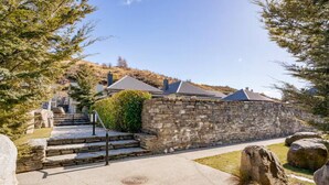 Un bâtiment aux murs de pierre, avec un escalier menant à une porte, entouré d’arbres et sous un ciel dégagé.