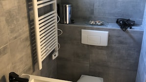 Een kleine badkamer met een wit wastafel, toilet en handdoekhouder.