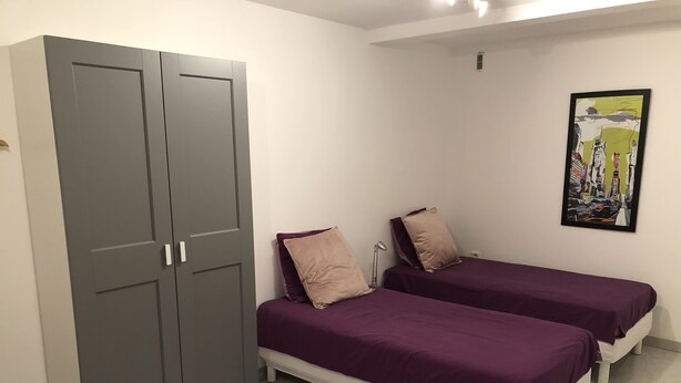 Een slaapkamer met twee bedden, een garderobe en een schilderij aan de muur.