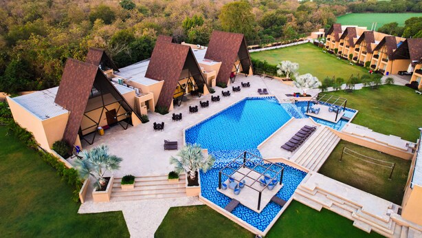 A resort with multiple bungalow-style buildings, a central swimming pool, and a well-maintained lawn. - Jagira Ananta Elite Gir (Talala)