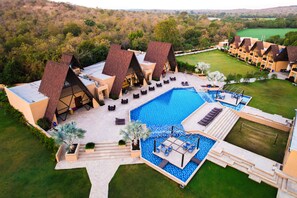 A resort with multiple bungalow-style buildings, a central swimming pool, and a well-maintained lawn. - Jagira Ananta Elite Gir (Talala)