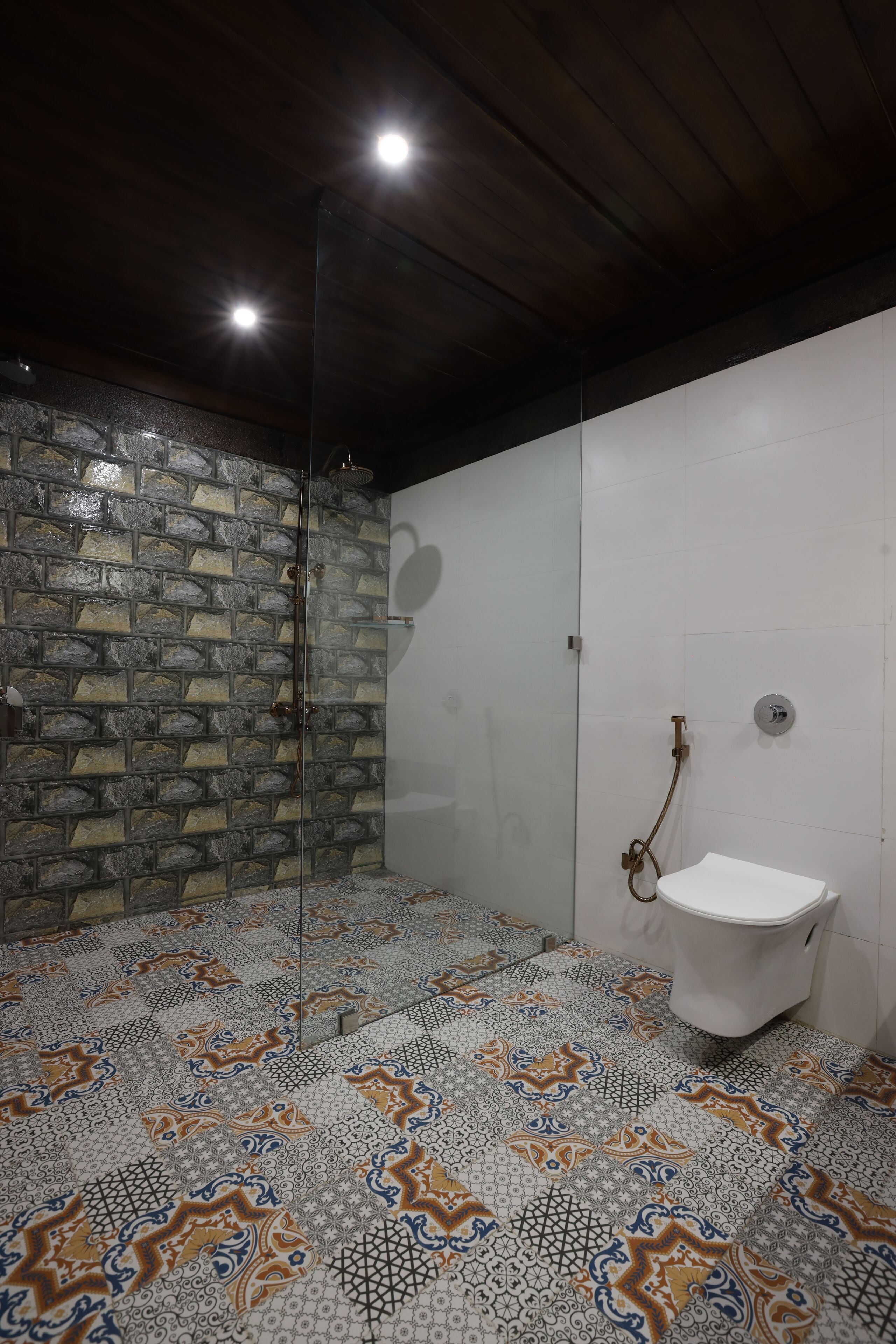 Ein Badezimmer mit Steinwand, Duschkabine aus Glas und Fliesen mit Muster.