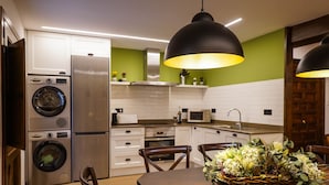 Une cuisine moderne dotée d’appareils électroménagers en acier inoxydable, un coin repas avec une table en bois et un mur d’accent vert.