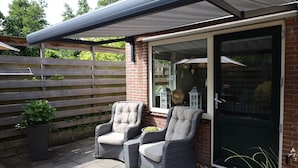 En terrasse med to fletstole og en potteplante.