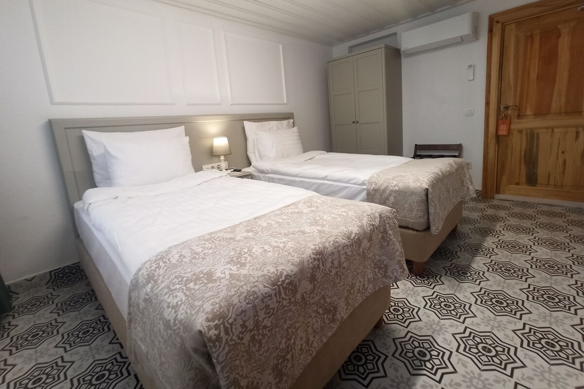 A hotel room with two beds, a wardrobe, and a patterned floor.